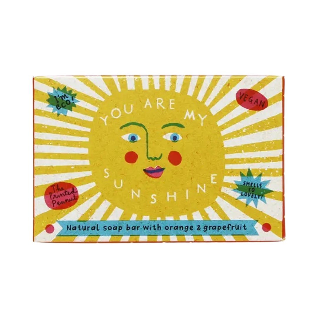 A packaged bar of handmade soap with orange and grapefruit, labeled 'You are my sunshine' with a sun and rain design in the background.