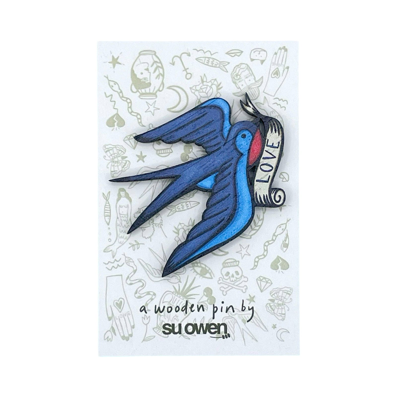 Swallow-shaped wooden brooch featuring a blue swallow holding a white entwined banner with the text 'Love' in its beak.