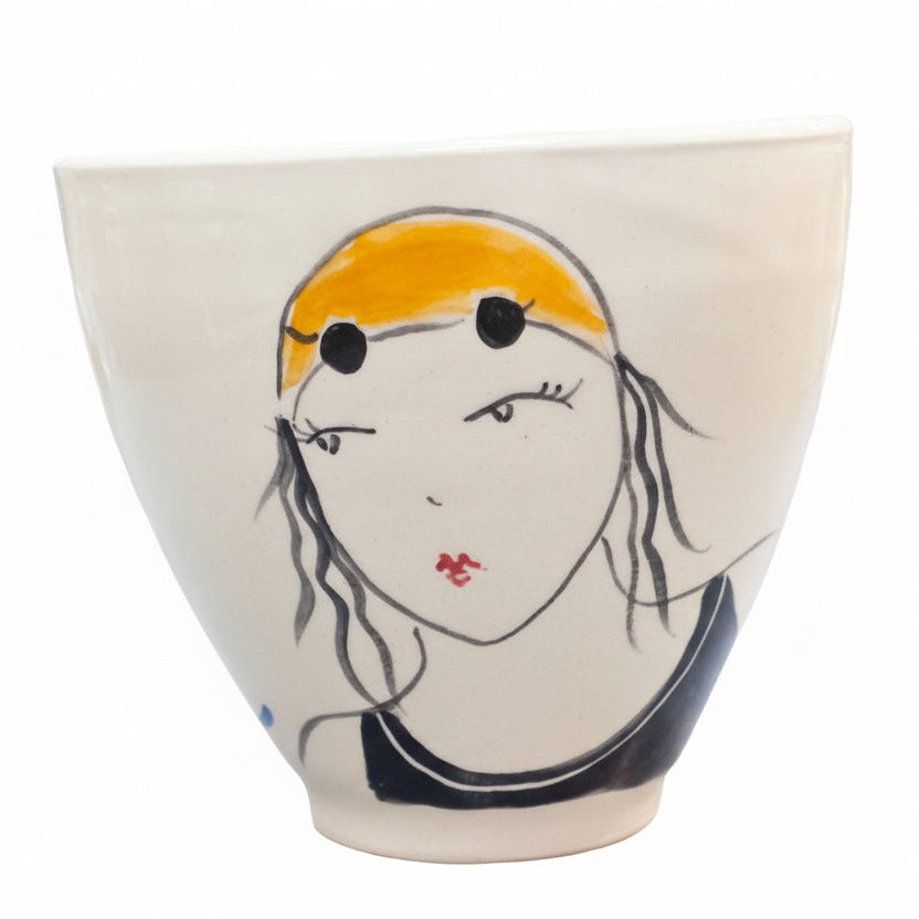 Ceramic cup with a face and yellow hat on a white background.