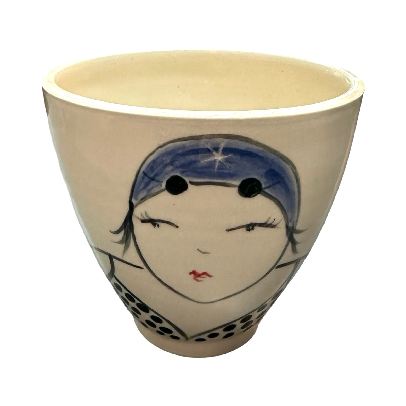 A cream ceramic beaker with a female wild swimmer on the front wearings a blue polka dot swimsuit and a blue swim cap.