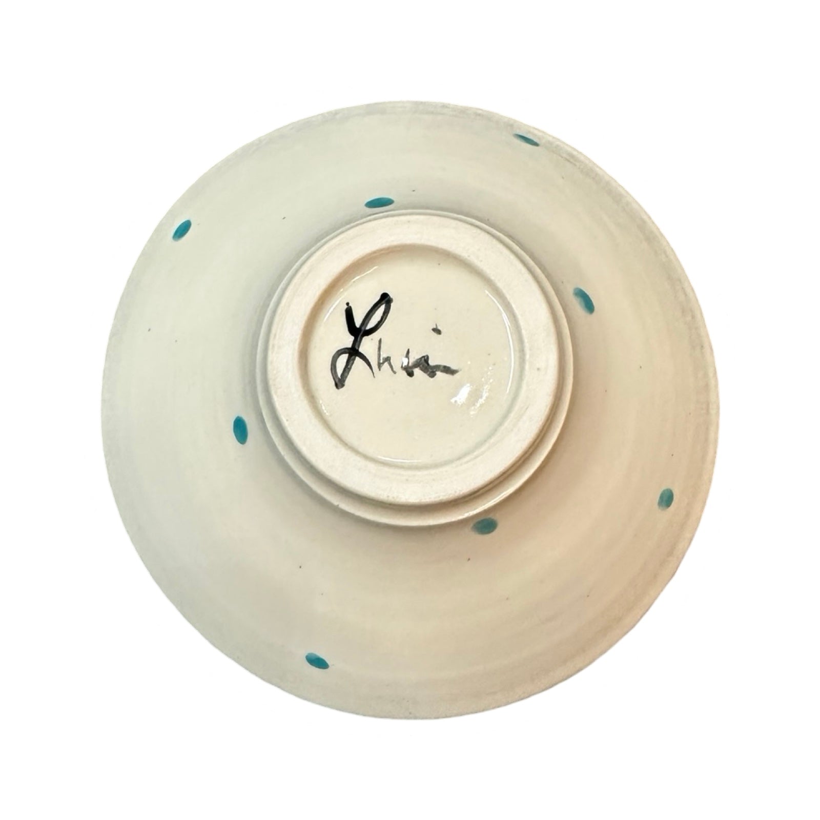 The base of a cream ceramic cereal bowl with turquoise polka dots.