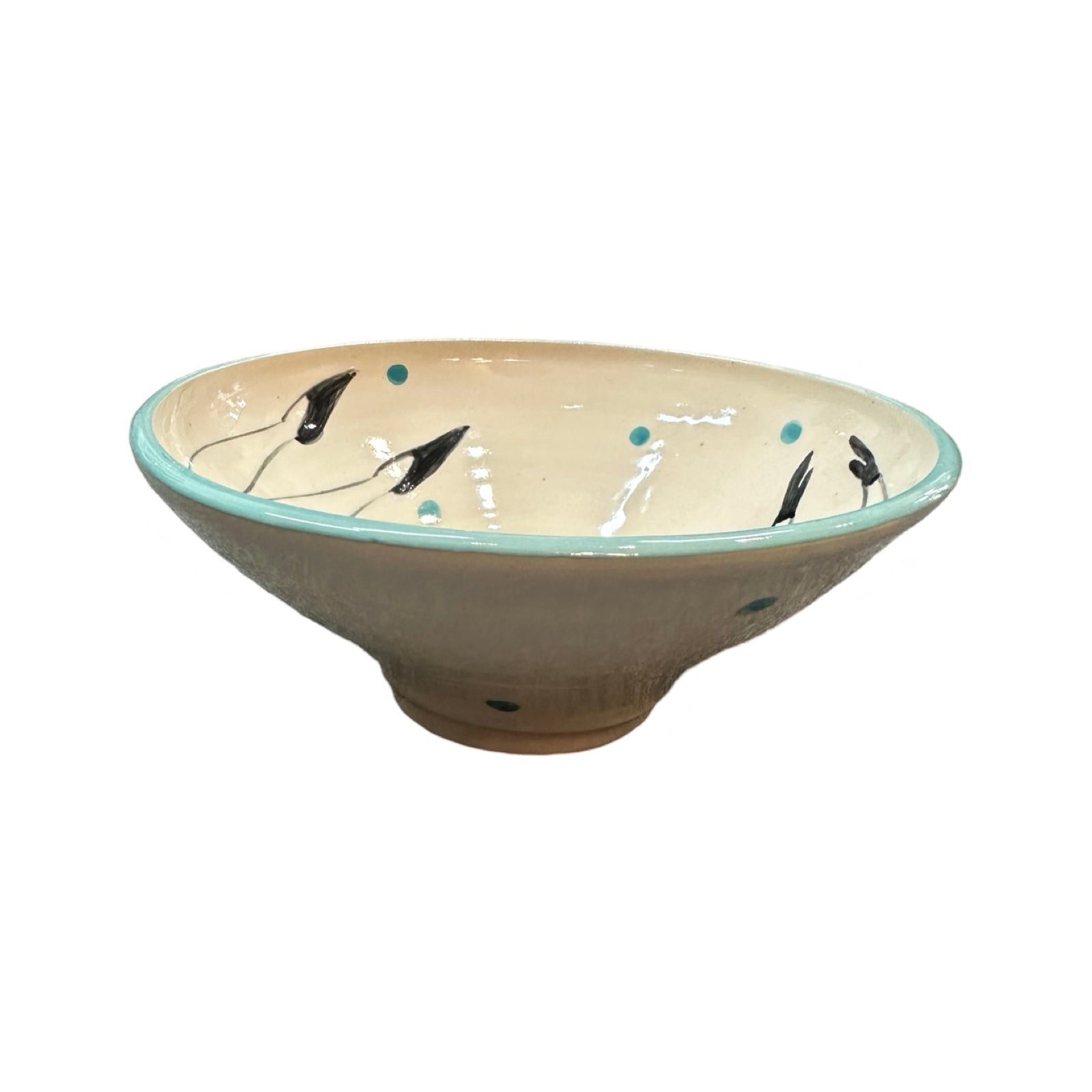 The side of a cream ceramic cereal bowl with a turquoise rim and turquoise polka dots.