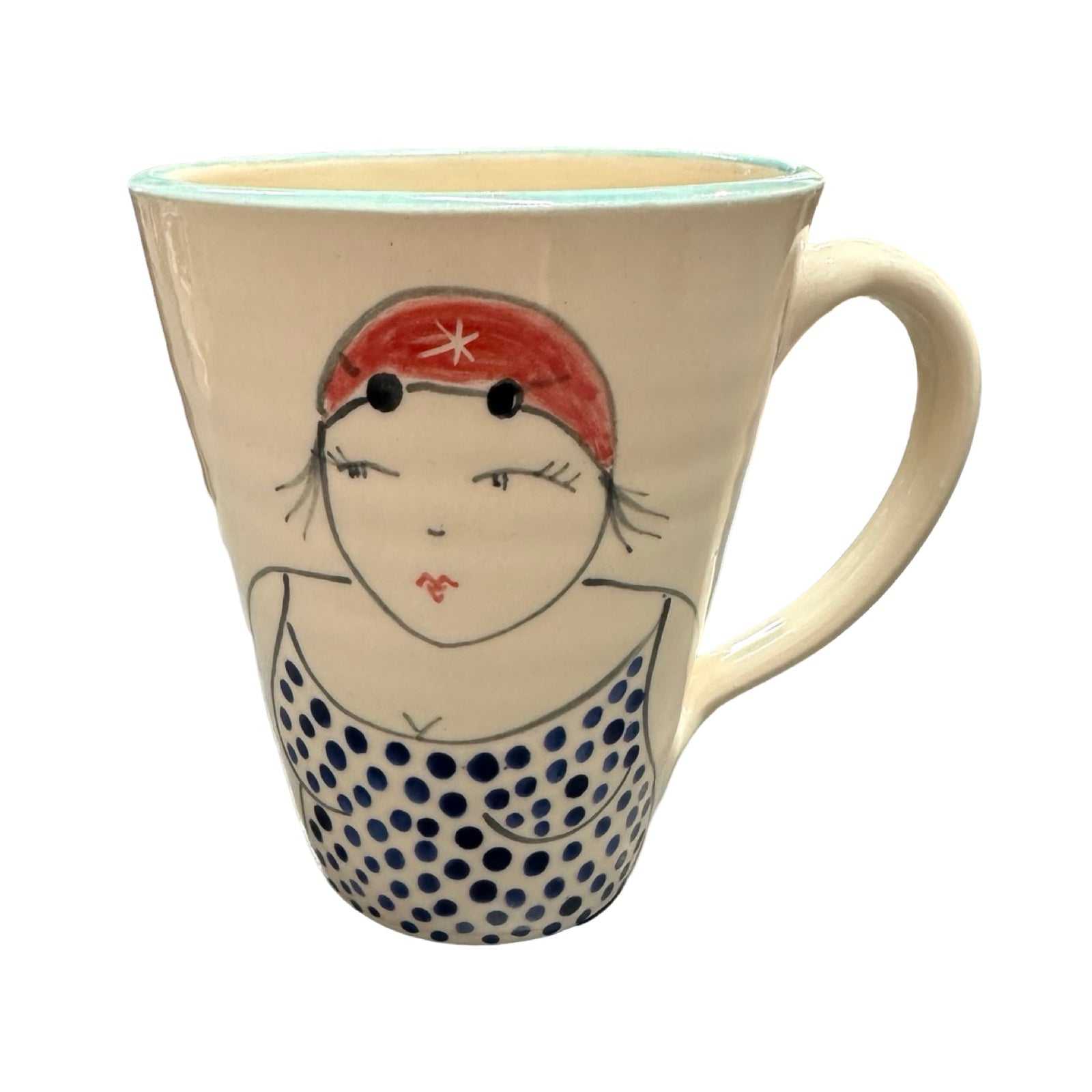 A cream coloured ceramic mug with a female wild swimmer wearing a blue polka dot swimsuit and a red swim cap.