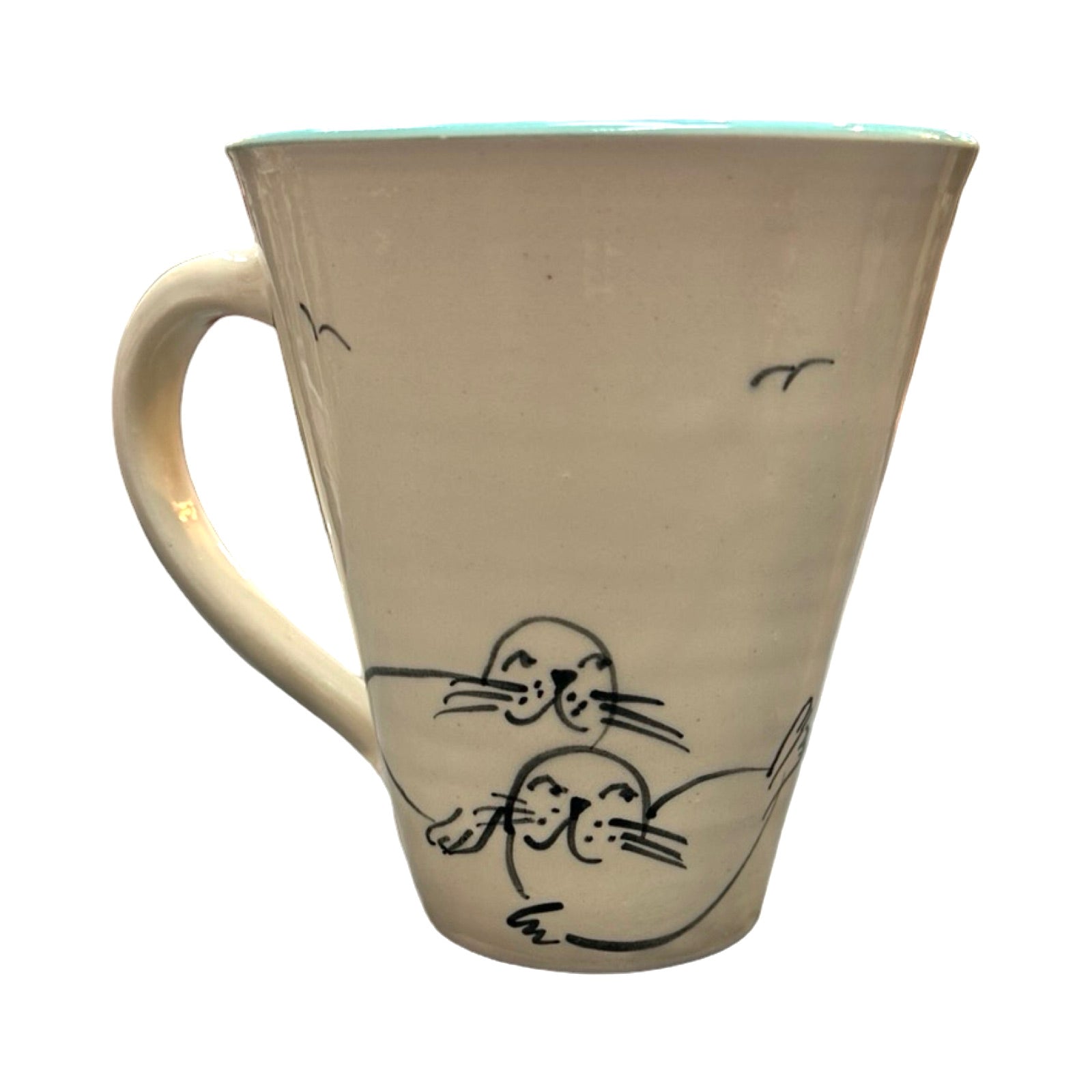 The back of a swimmer mug with two cute seals and two black seagulls flying above.