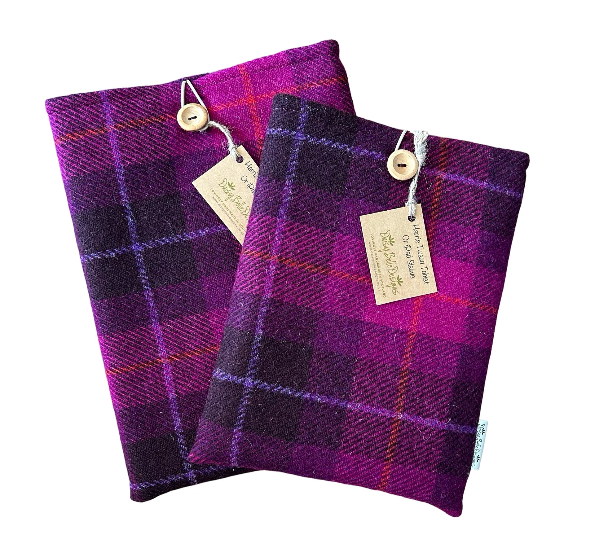Two Harris tweed tablet sleeves in dark pin tartan check.  The sleeves have an elastic loop and wooden button at the top. Shown here with a Daisy Belle Designs branded label.