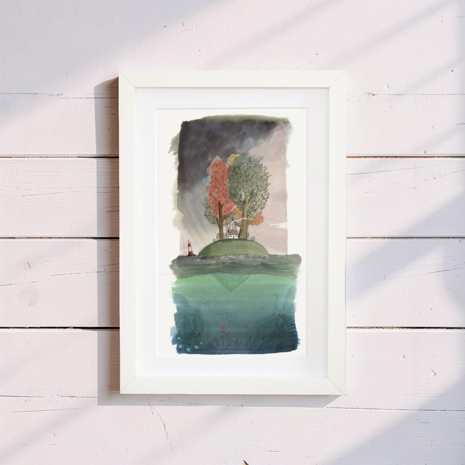 Framed artwork of a landscape with trees and water on a wooden surface.