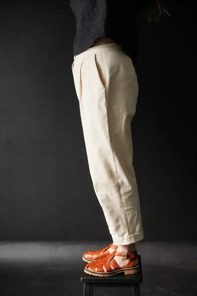Sewing pattern for a pair of 'peg' trousers featuring a fly front, angled pockets and turn-ups.