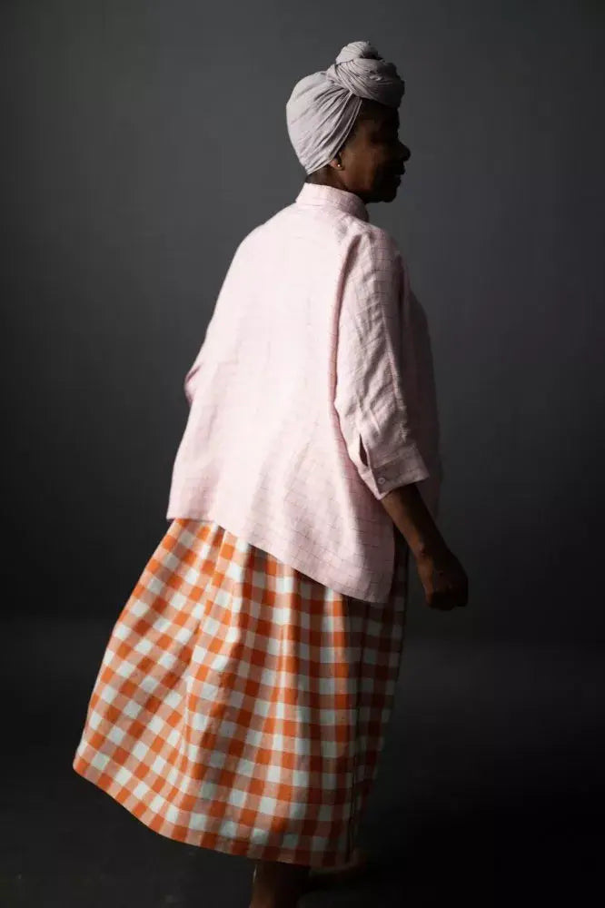 Sewing pattern for an A-line skirt with slanted pockets, side button fastenings and pleats for fullness.
