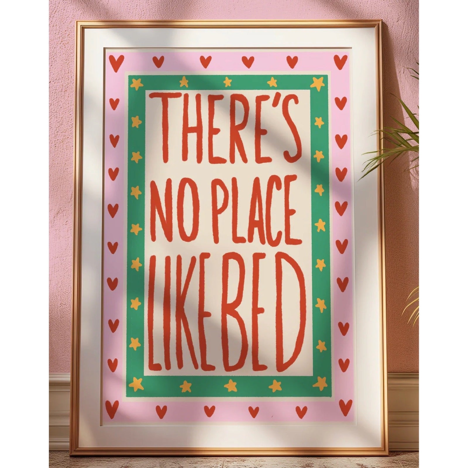 Framed print with 'There's no place like bed' text on a pink background.