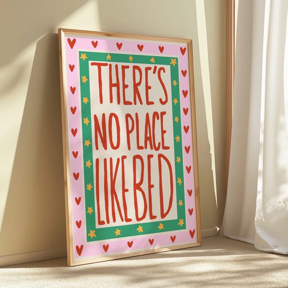 Framed print with 'There's no place like bed' text on a pink background.