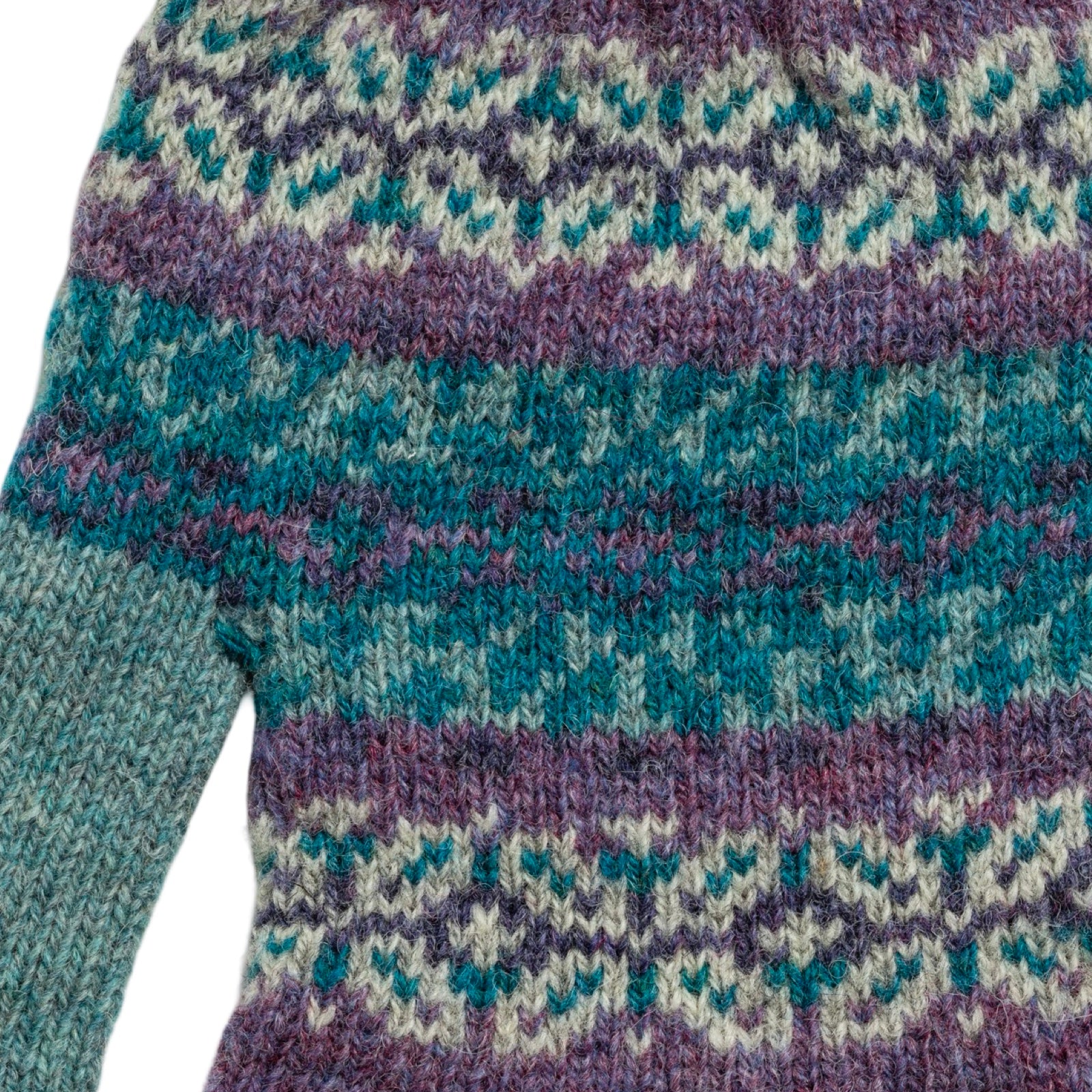 Close-up of a knitted sweater with a patterned design on a white background.