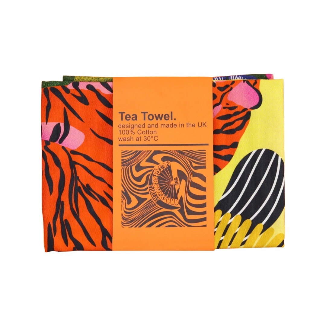 Tea towel featuring a colourful illustration of a sitting tiger in the jungle folded with a belly band.