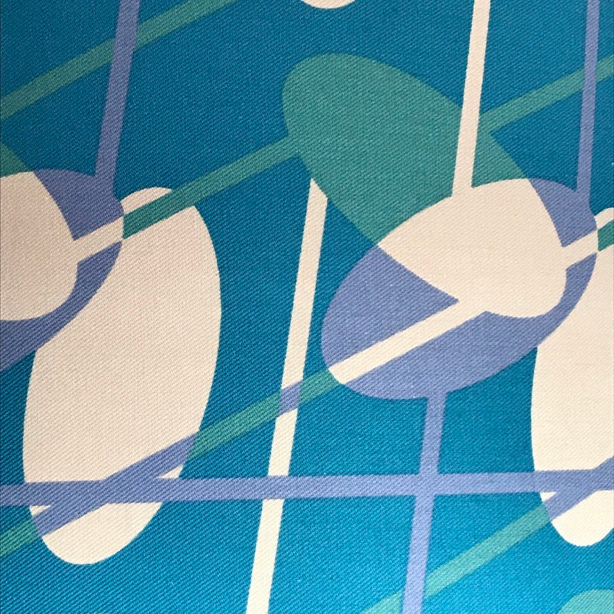 Teal fabric with a mid-century inspired design in a purple, turquoise and off-white