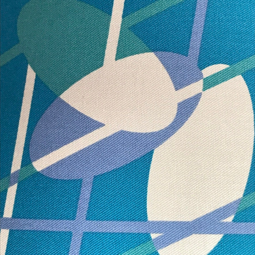 Teal fabric with a mid-century inspired design in a purple, turquoise and off-white
