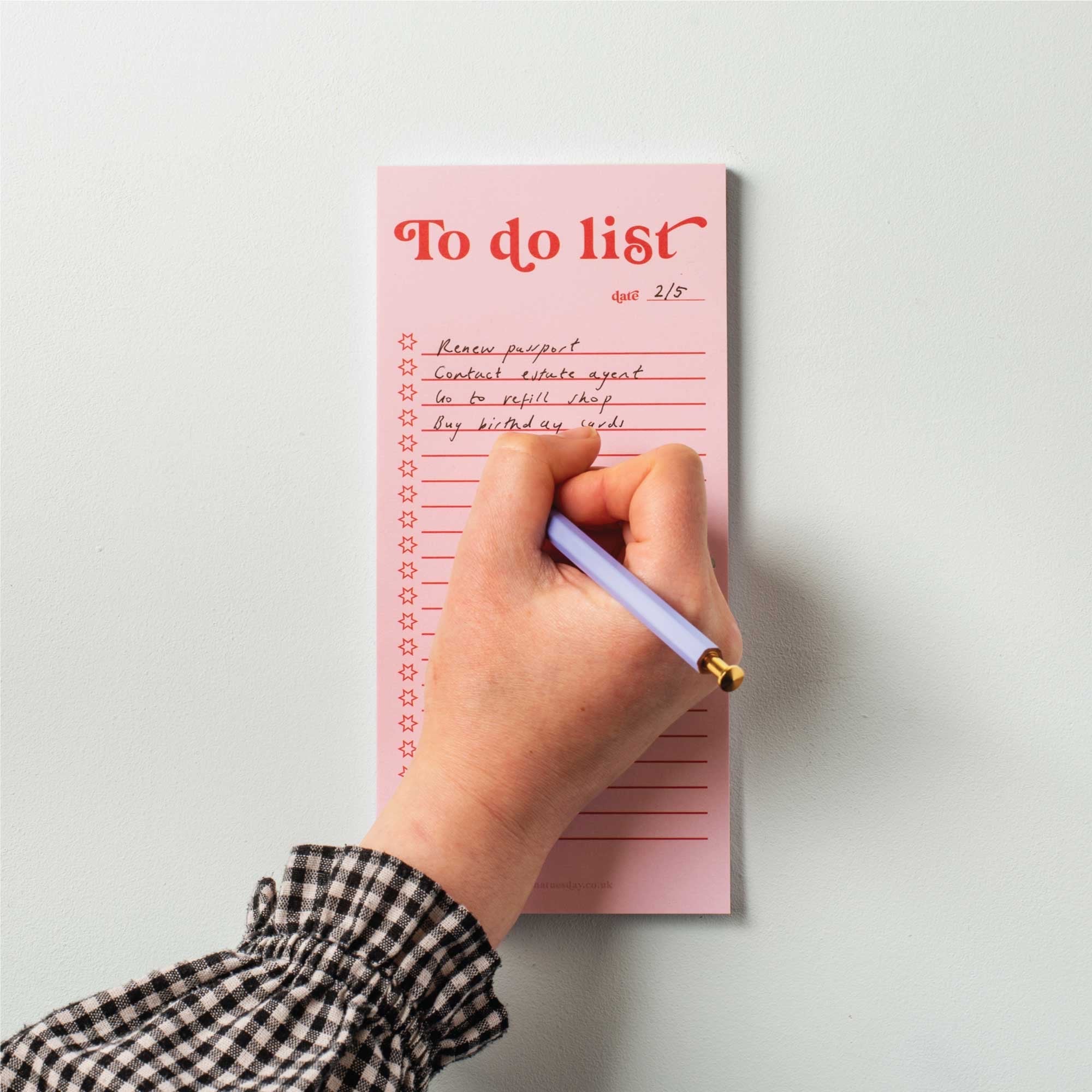 Hand writing on a pink 'To do list' notepad with a pen.