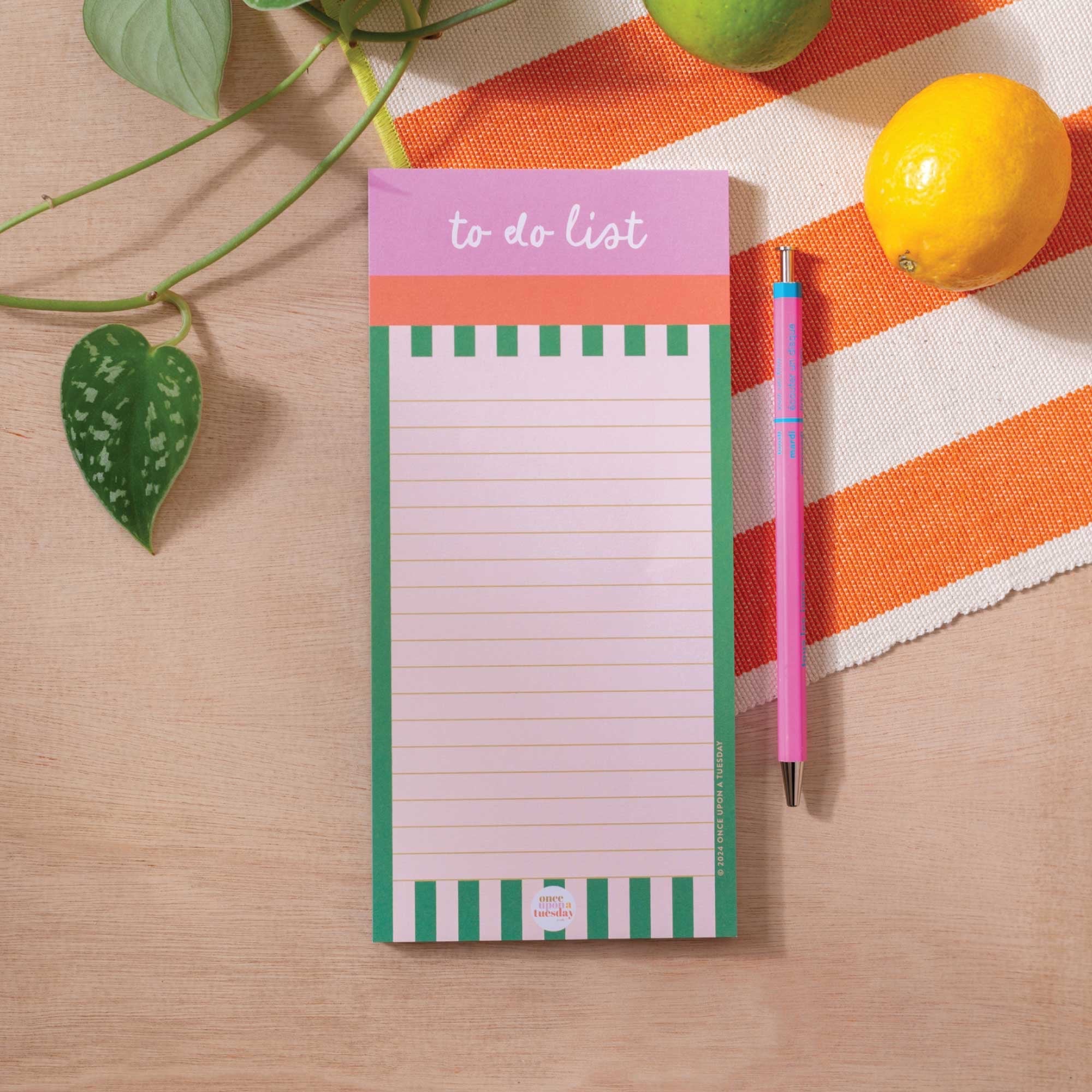 Notepad with 'to do list' on a striped tablecloth next to a pen and lemon.