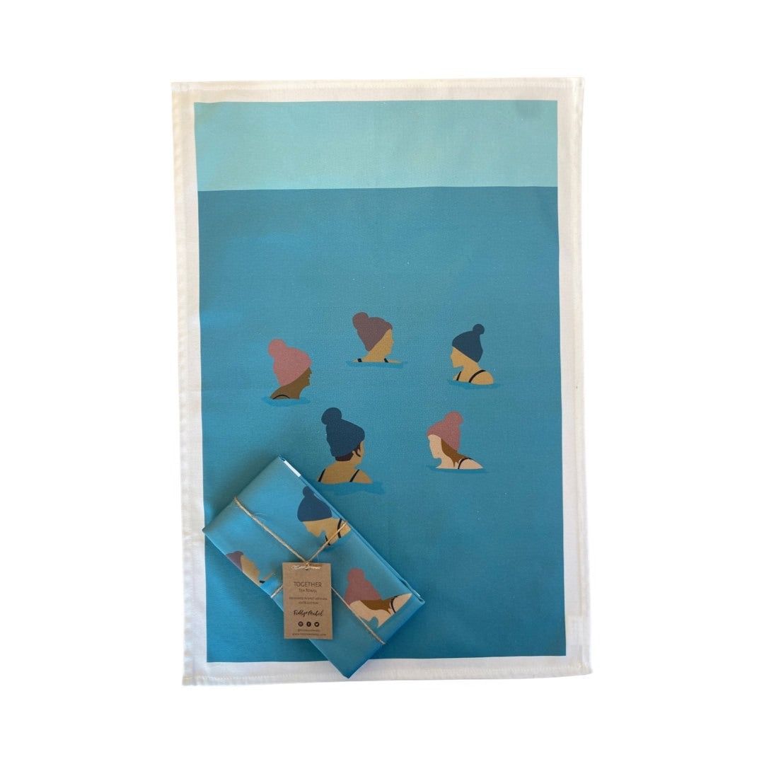 Tea towel featuring a group of wild swimmers in their woolly pom-pom hats up to their shoulders in the sea.