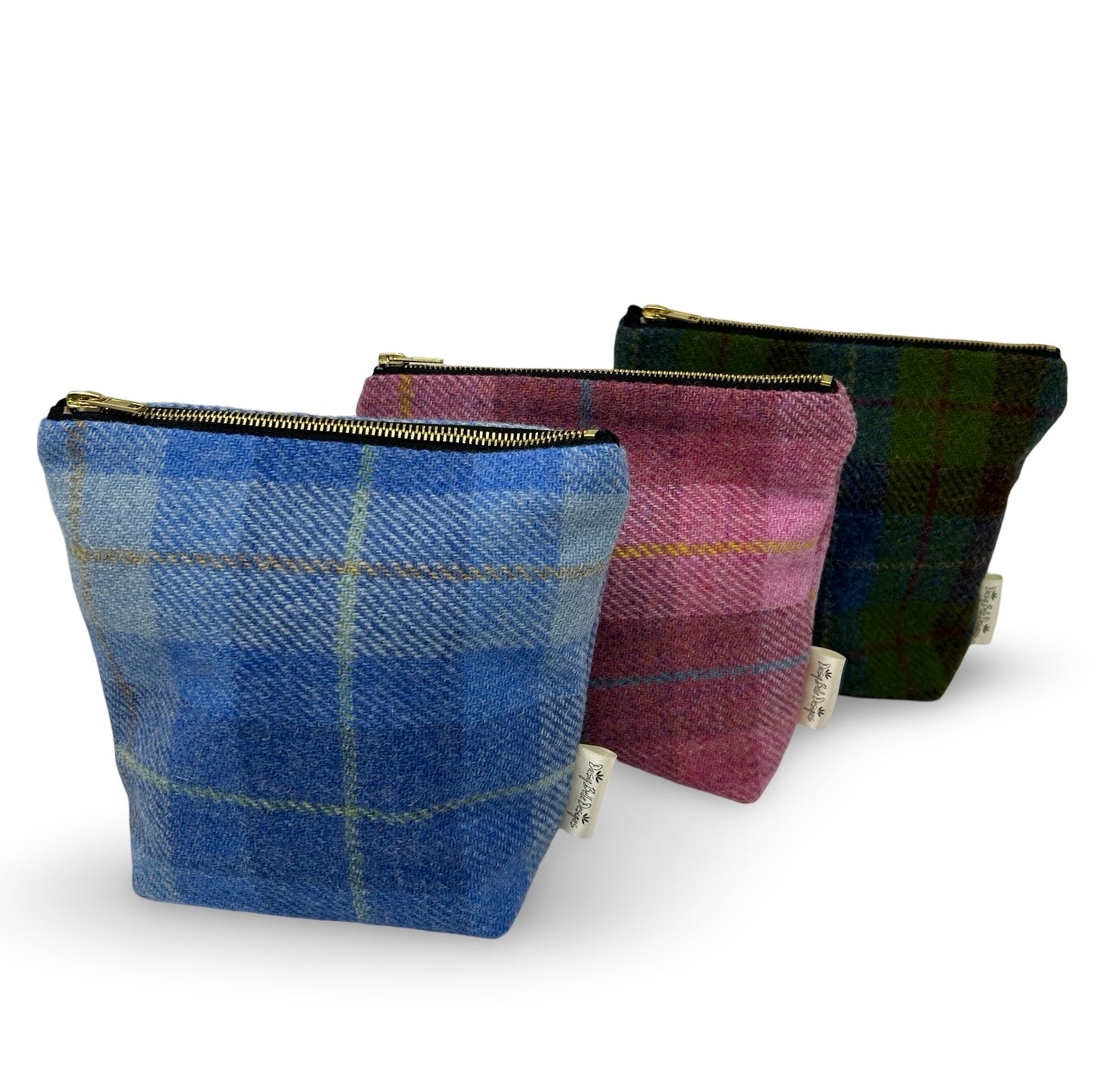 Three Harris tweed toiletry bags in a choice of pale blue, pink or dark blue and green check.  Each bag has a gold zip at the top and a Daisy belle Designs brand label in the side seam.