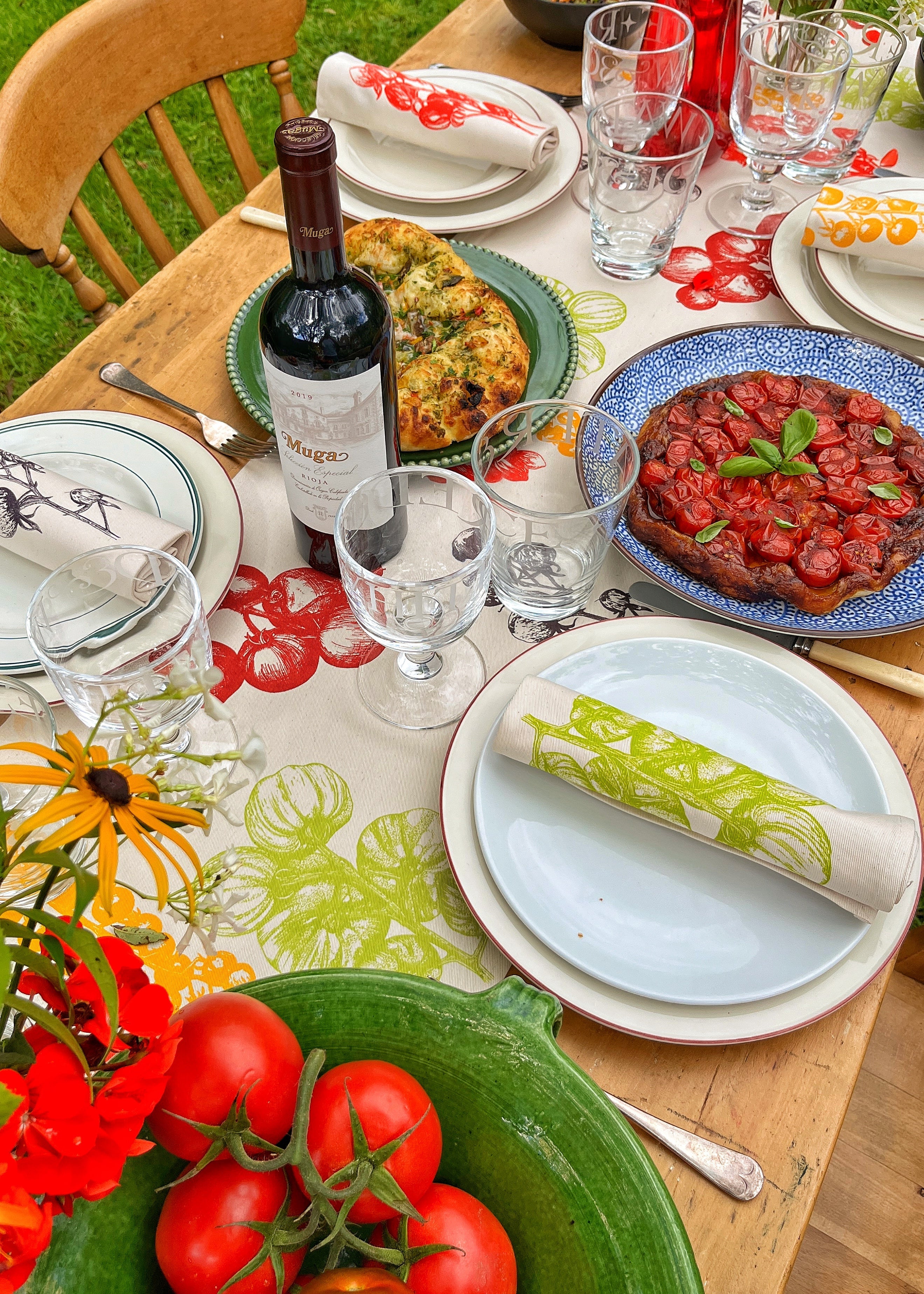 Dining table set with food, wine, and tableware outdoors.