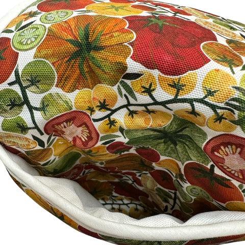 Oven gloves featuring red, orange and yellow tomatoes with green foliage on a white background.