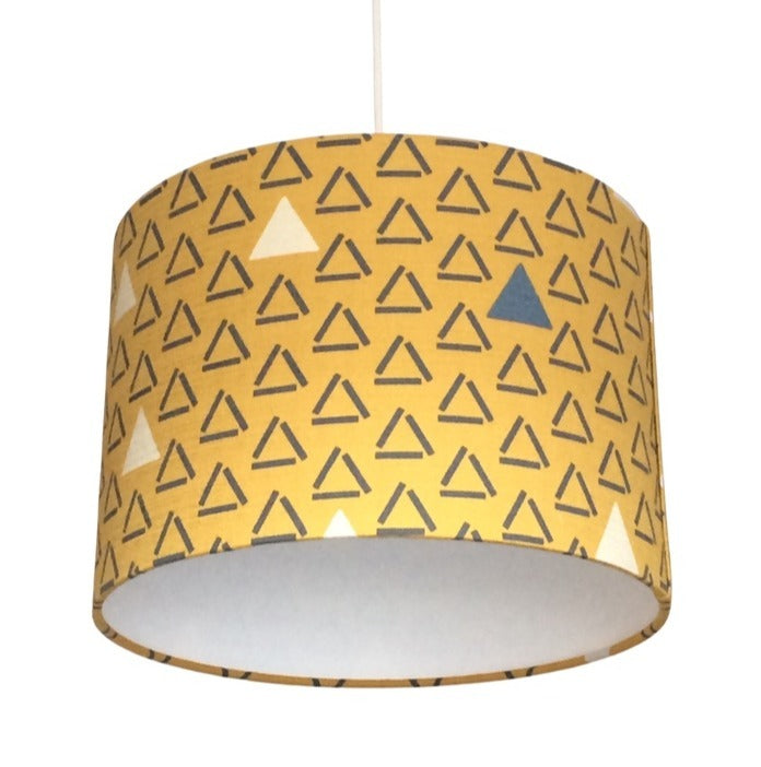 Close up of a drum lampshade covered in mustard barkcloth with grey open triangles and white closed and filled triangles