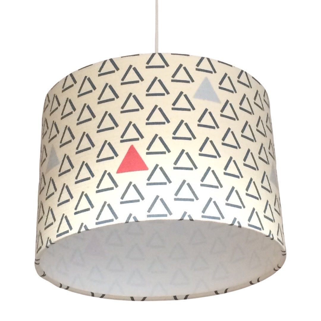 Close up of a drum lampshade with a white background, blue open triangles and red closed and filled triangles