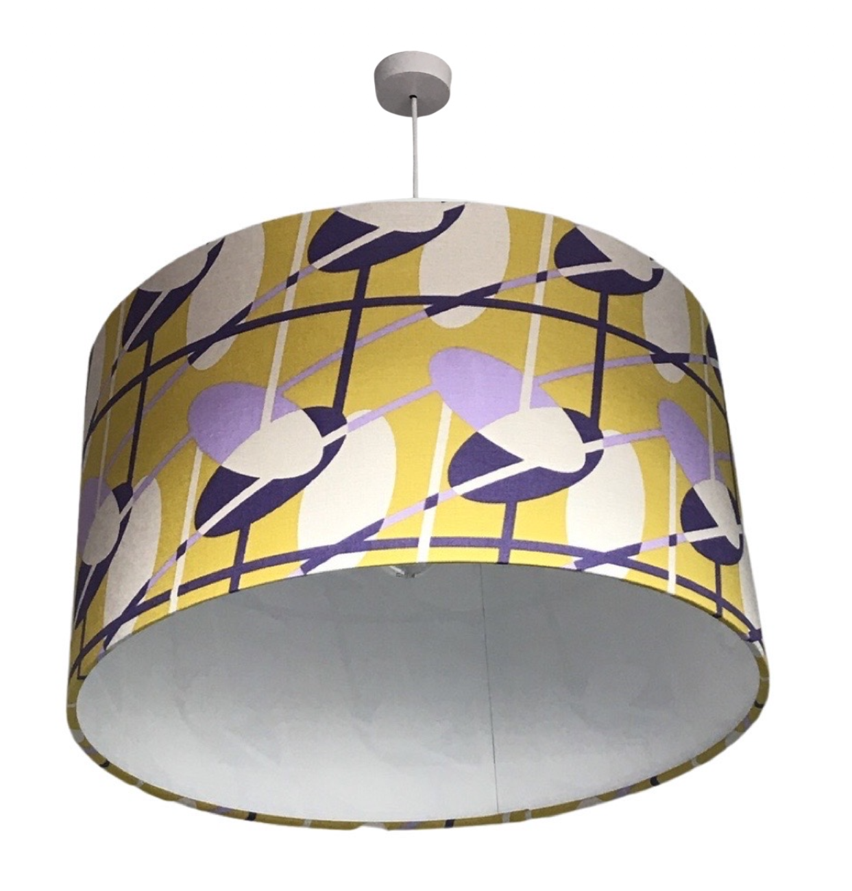 Drum lampshade covered in mid-century inspired fabric in a purple and off-white pattern against a yellow background
