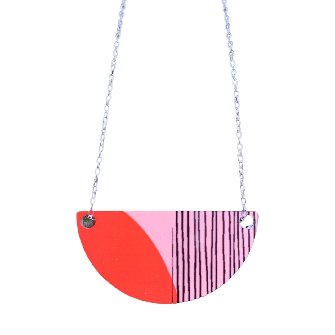 Hand printed aluminium arc shaped necklace with a red and pink abstract design and a Sterling Silver 18" chain.