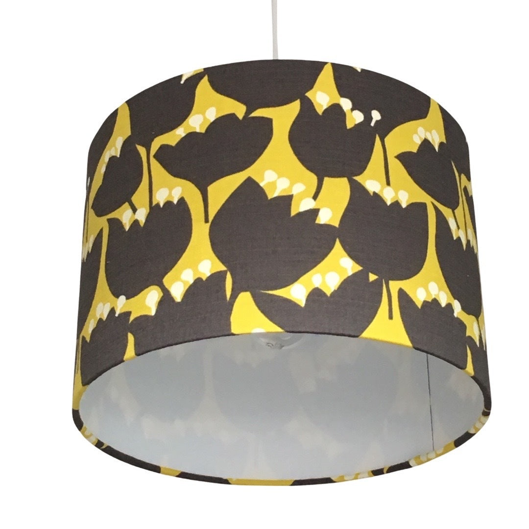 Close up of a drum lampshade with a mustard background and brown tulips with white tips
