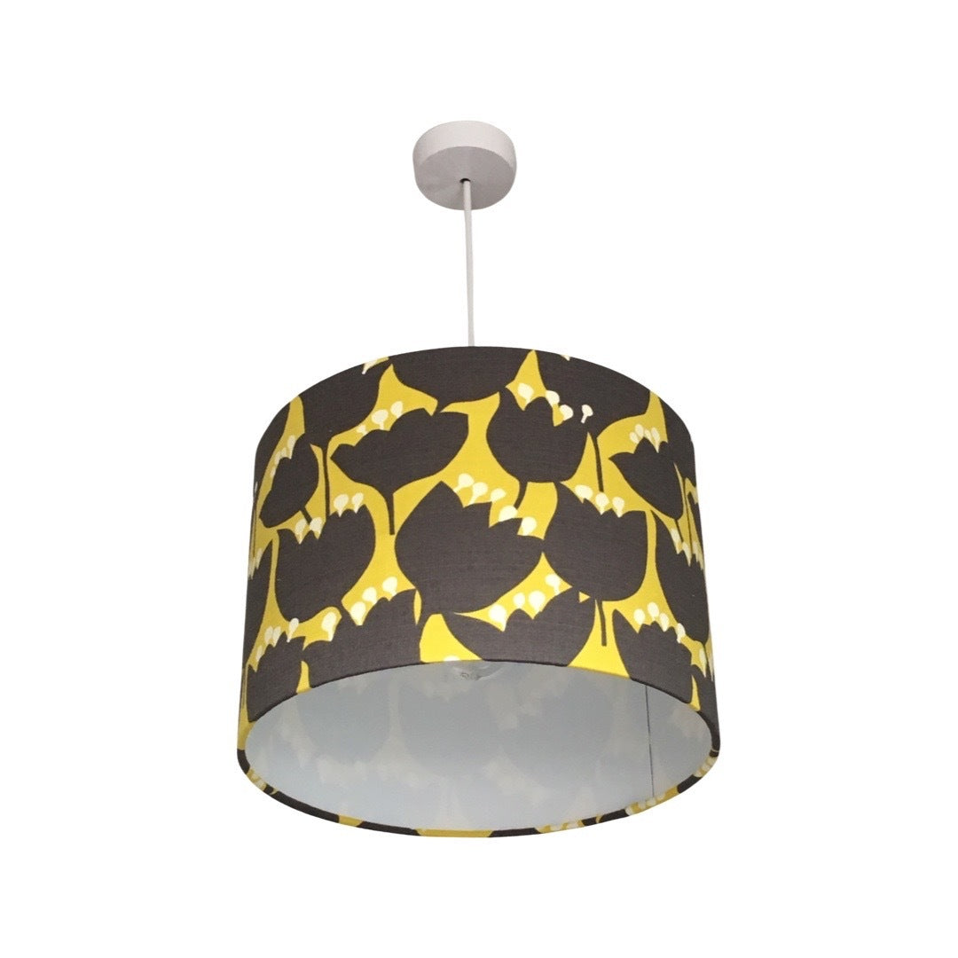 Close up of a drum lampshade with a mustard background and brown tulips with white tips