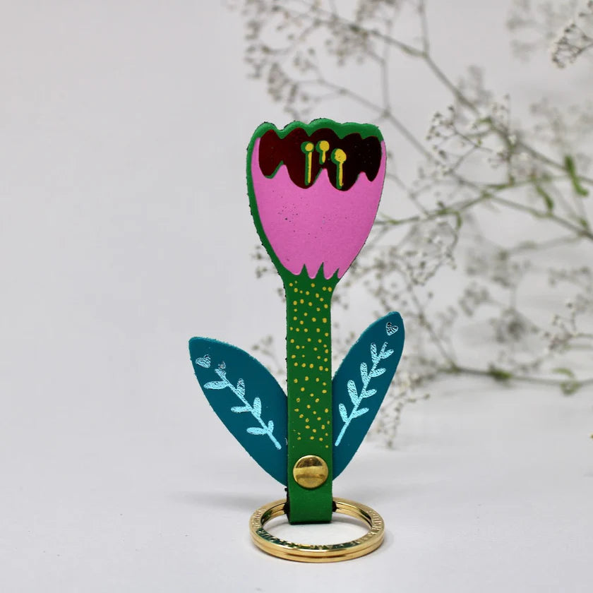 Colourful flower-shaped key ring with a pink centre and green stem on a white background.
