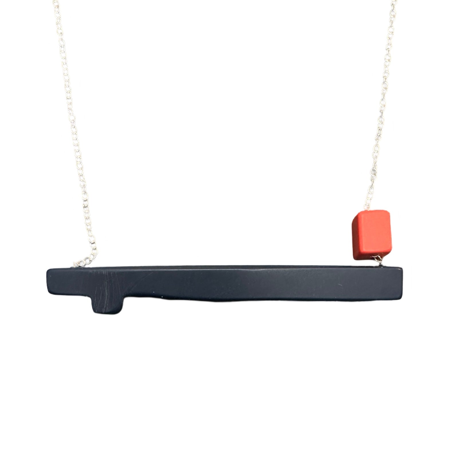 Navy twig shaped necklace with a small coral bead on the right side, hanging from a silver chain.
