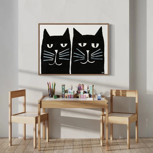 Children's table and chairs set with a black cat artwork on the wall.