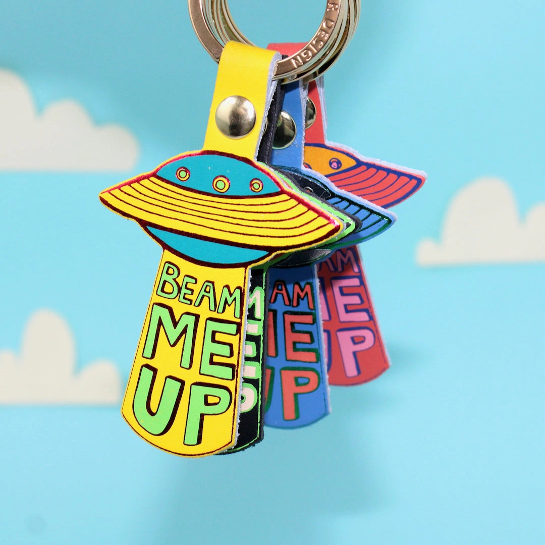 Colourful UFO key rings with 'Beam Me Up' text on a blue background.