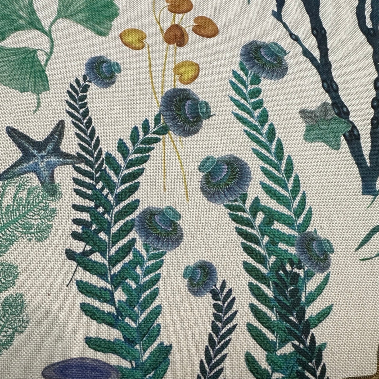 Cotton/linen fabric with underwater designs in green, blue and mustard.
