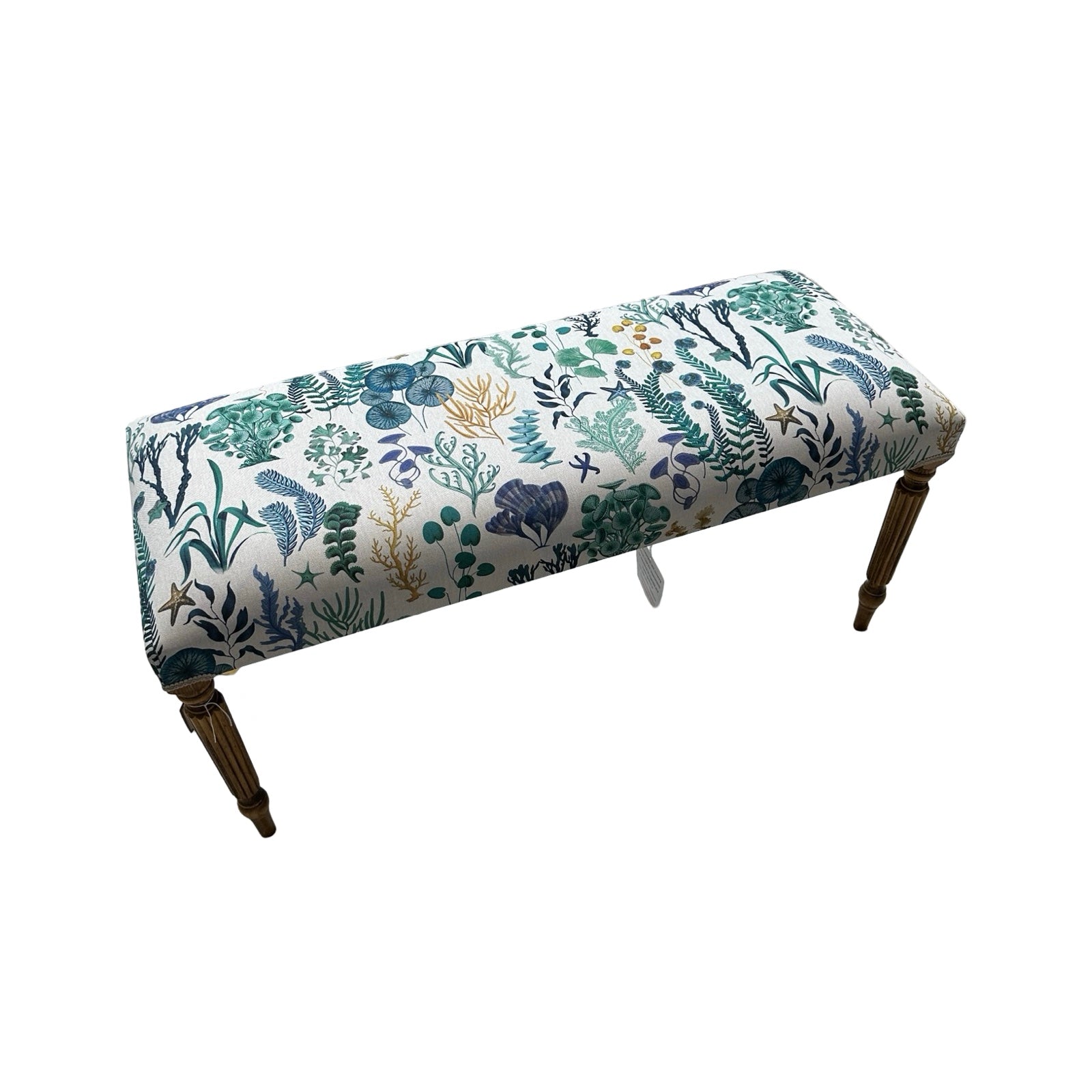 A rectangular bench covered in a cream cotton/linen fabric with underwater designs in green, blue and mustard, cream binding and mahogany stained legs.