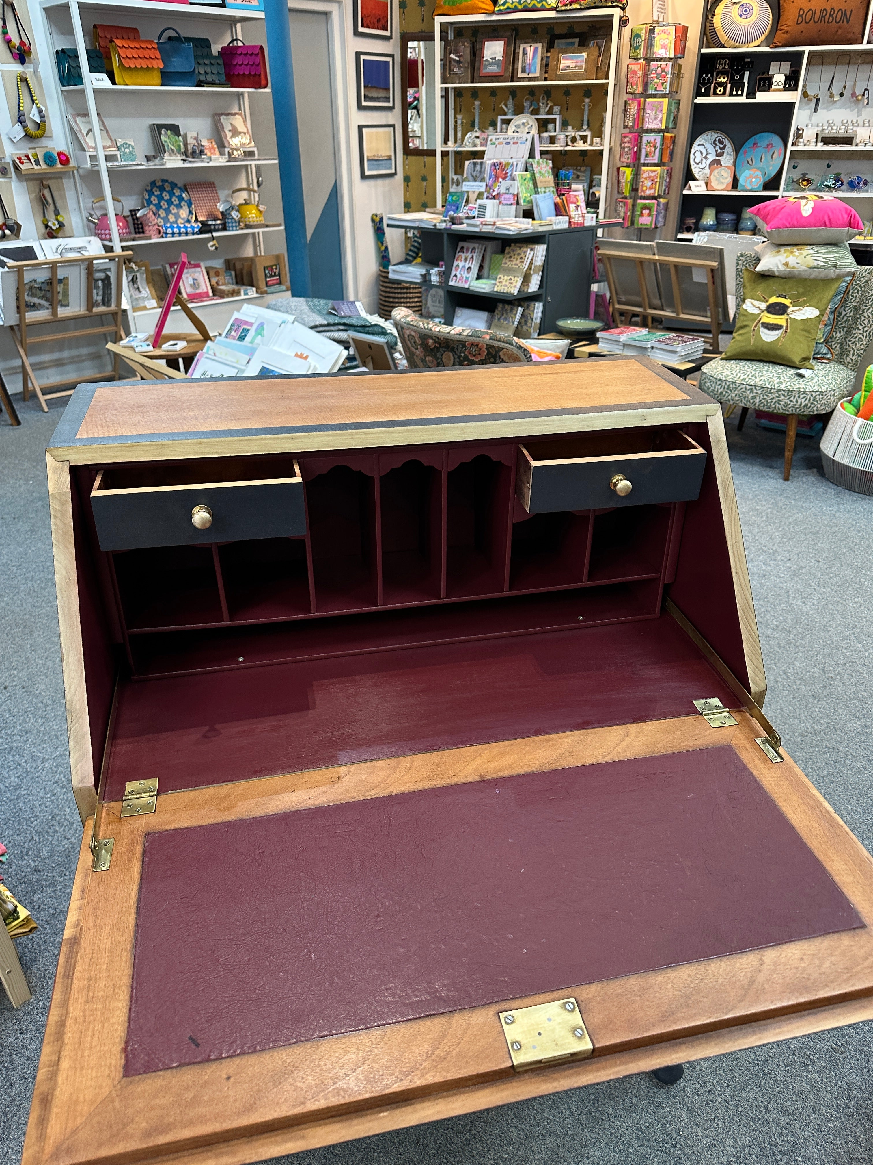 Wooden bureau with compartments on a carpeted floor.
