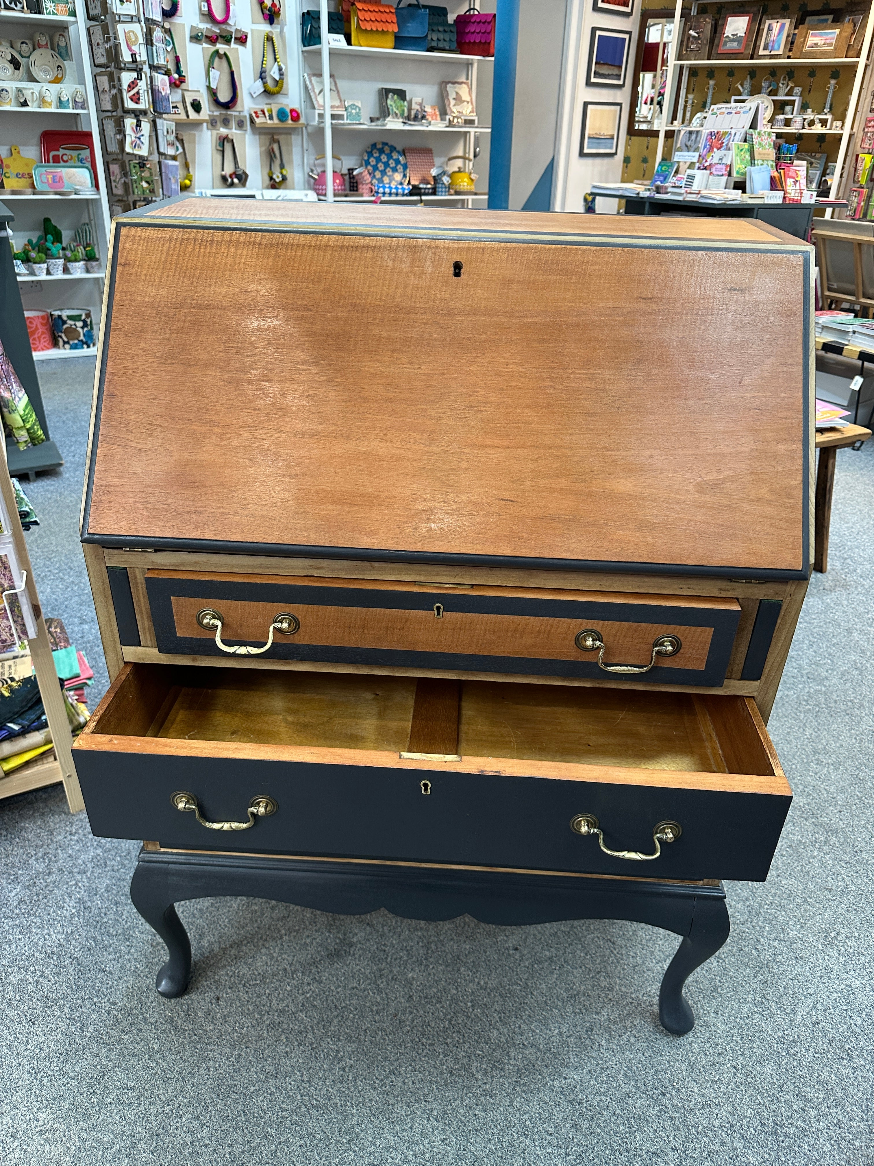 Wooden dresser with open drawer on a gray floor, surrounded by shelves with various items.