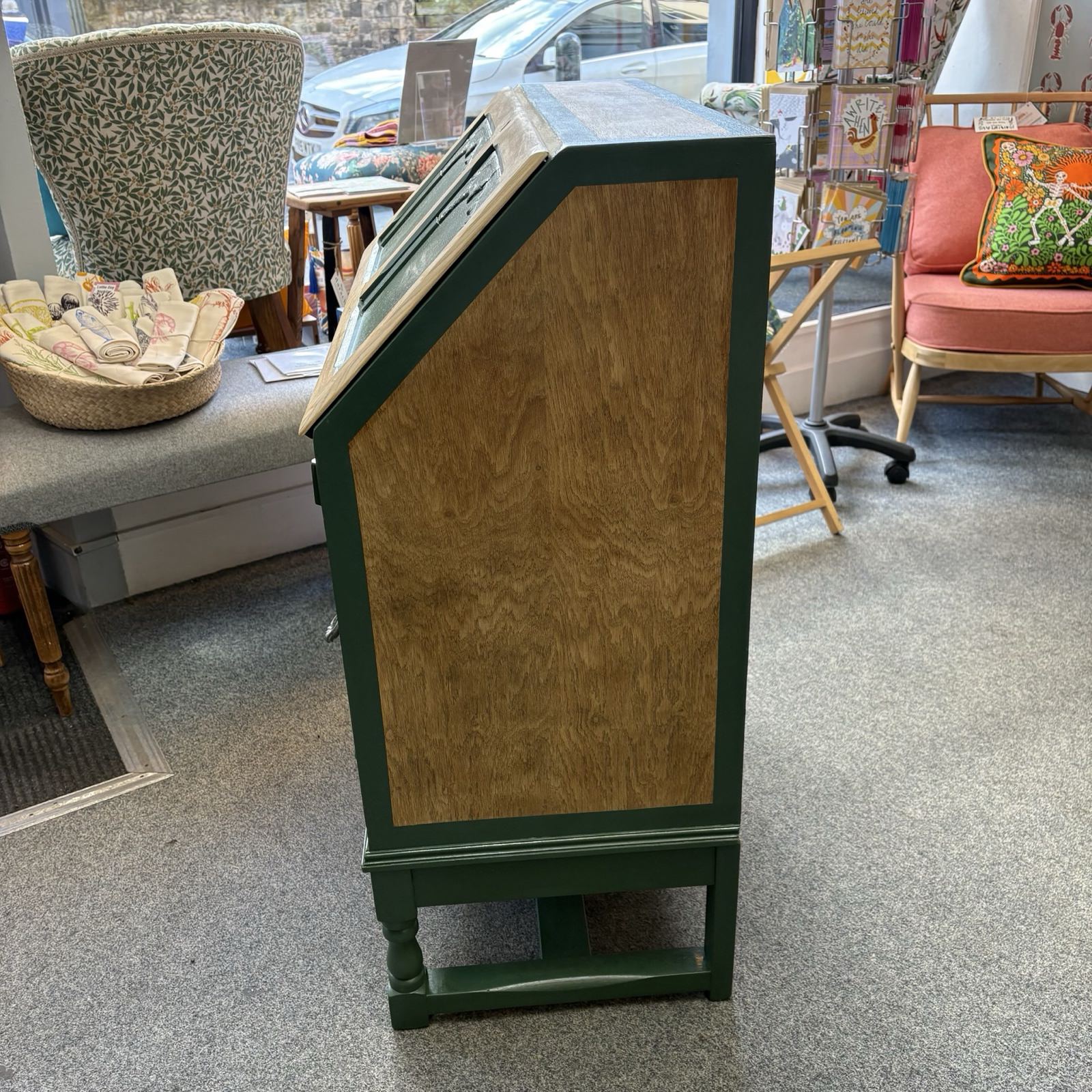Wooden display case with green base in a store setting.