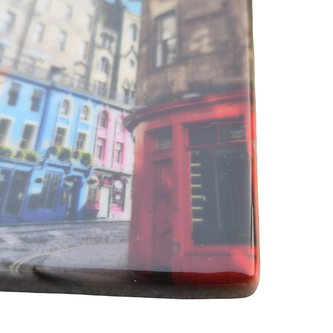 A close up of a ceramic magnet with a picture of Victoria Street Edinburgh printed on it.