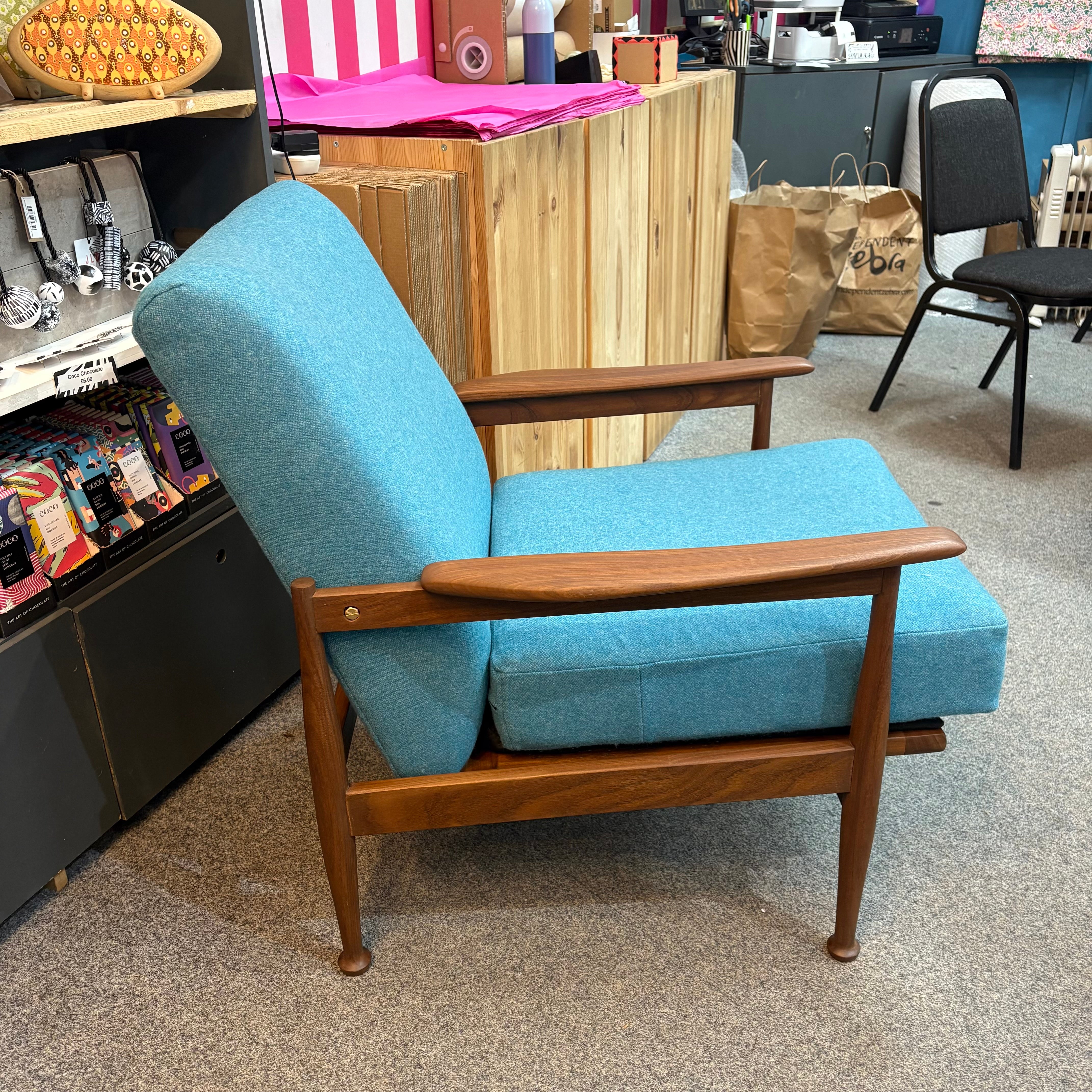 Blue armchair with wooden frame in a store setting.