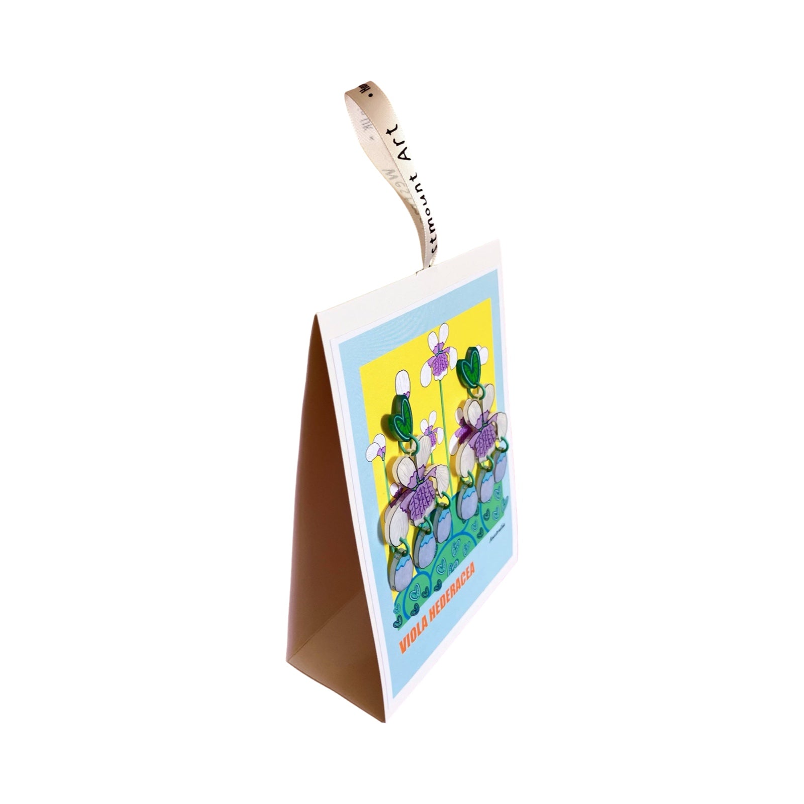 A pair of acrylic dangle earrings with green love heart studs, white and lilac viola flowers and lilac hanging petals, all on a matching backing card.