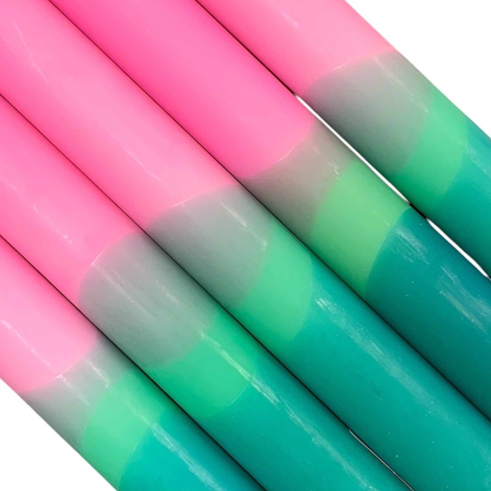 A row of 5 handmade dinner candles with a green base, a lighter green centre, and a pink top.