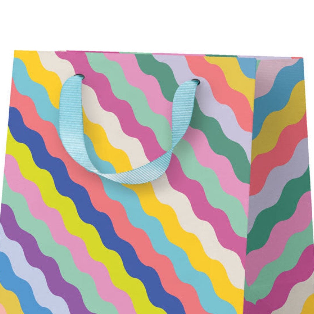 Colorful wavy patterned bag with a blue handle on a white background.