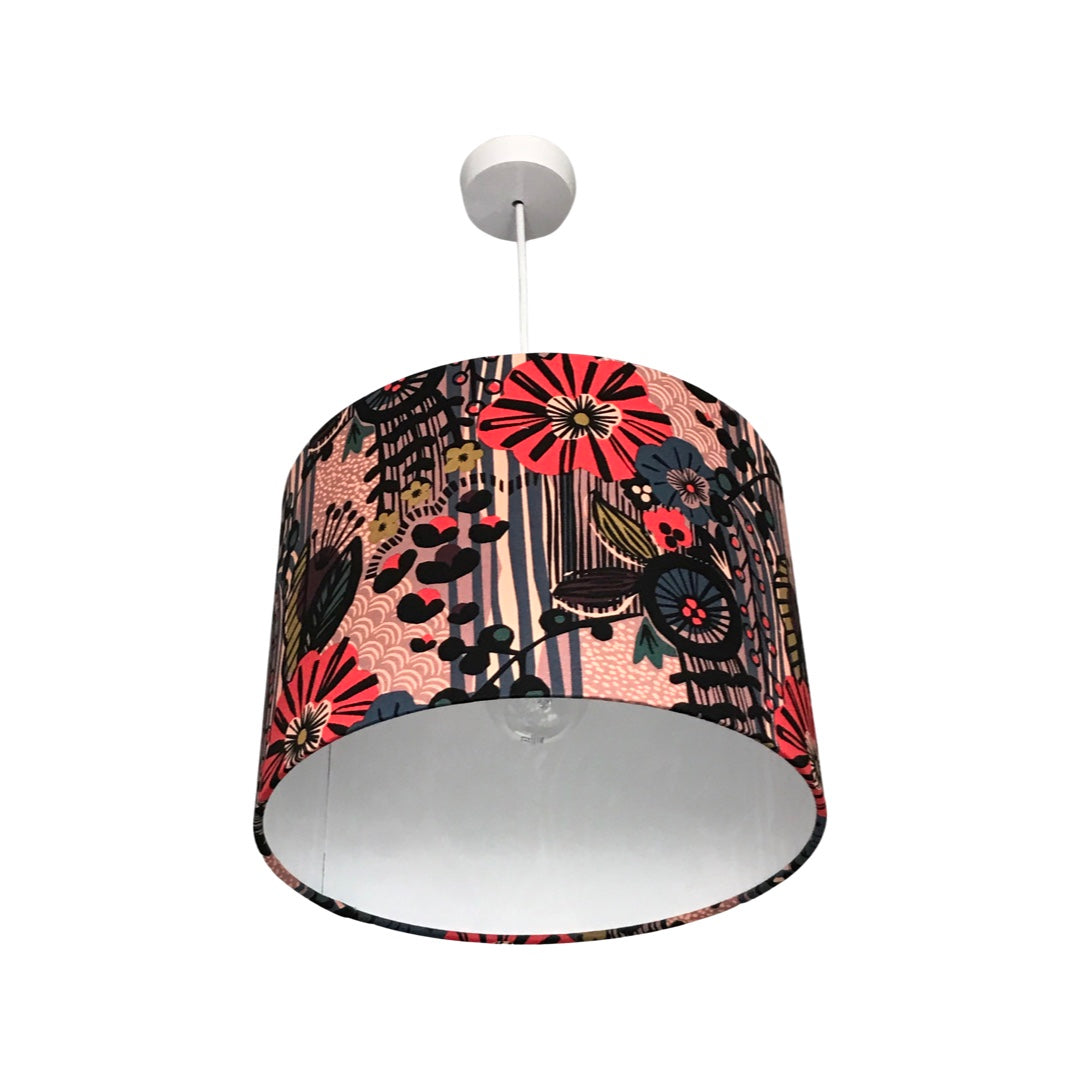 A drum lampshade covered in fabric featuring a black, red and blue floral pattern