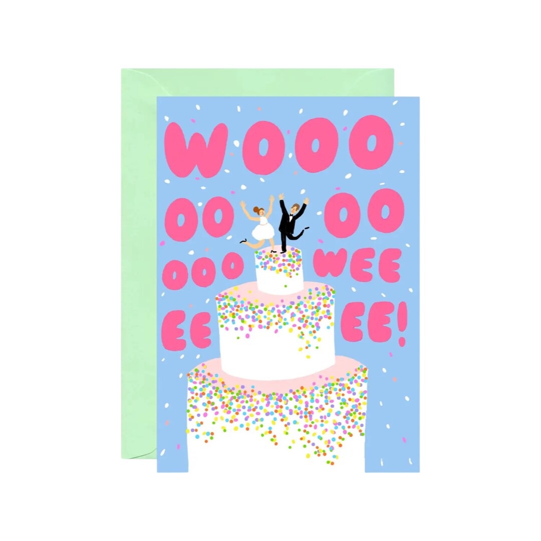 Wedding card featuring a giant white wedding cake with sprinkles and a bride and groom dancing on the top and the text 'Woooooooooooooweeeeeee' written in large pink text, all on a blue background.