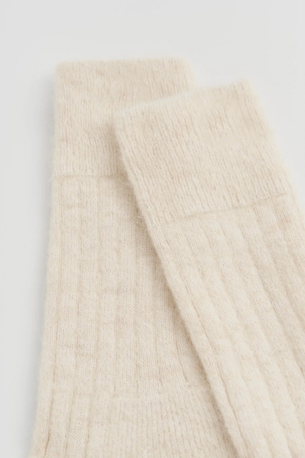 Beige ribbed knit socks on a white background.