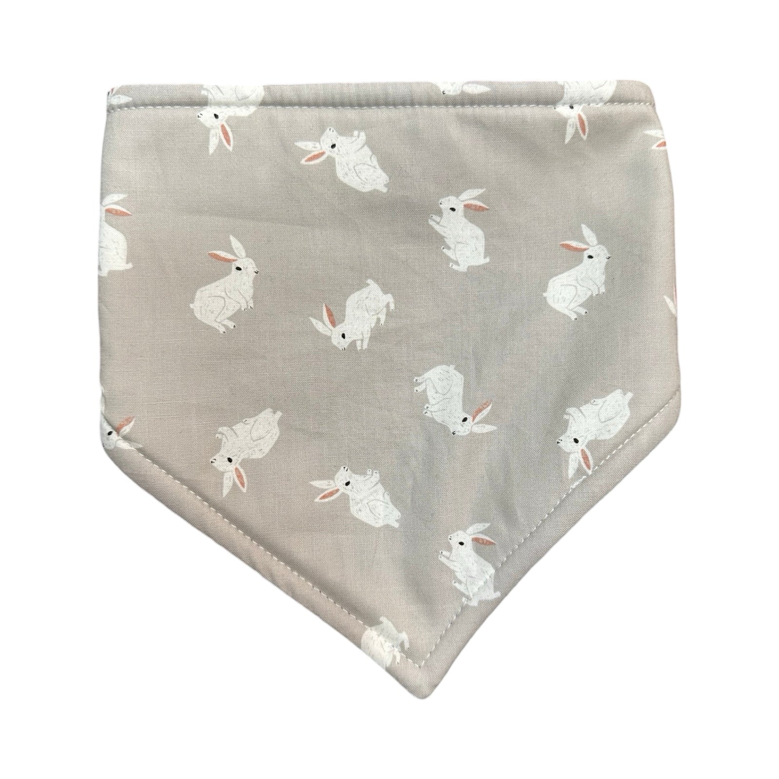 A baby bandana bib in grey cotton fabric with white rabbits.