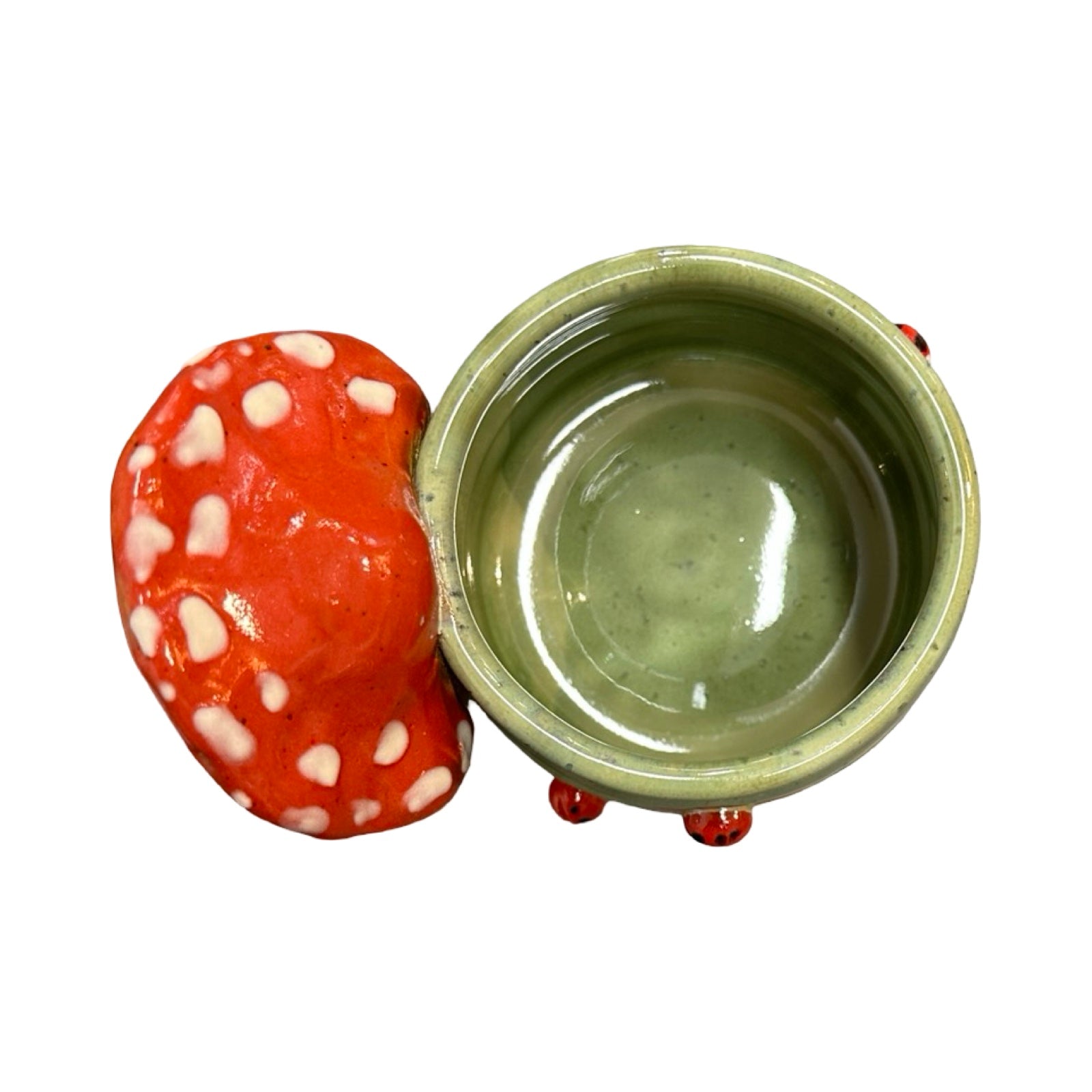 Red mushroom-shaped handle on a ceramic green mug on a white background.