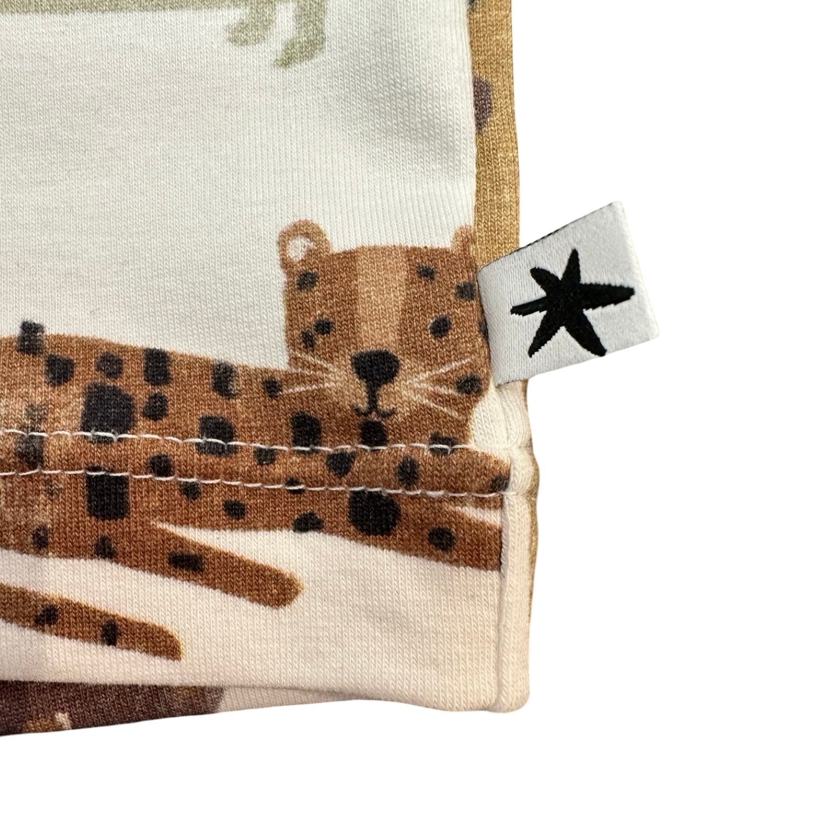 Close-up of a fabric with an animal design and a tag featuring a starfish symbol.